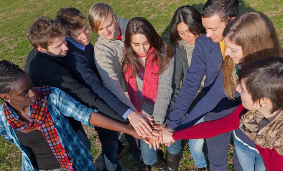 Schaffen Sie Begegnungen: Zum Beispiel
durch den gemeinsamen Besuch des Sportfests. Glücklich College-Studenten mit den Händen auf Stapel