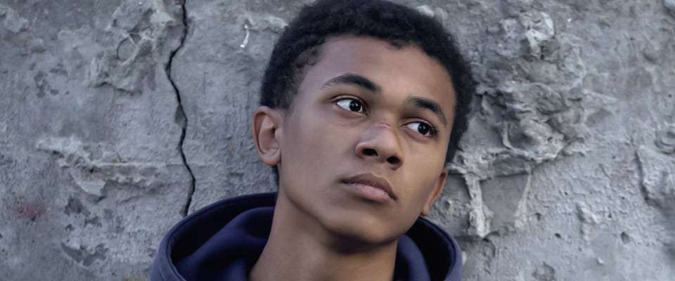 Ein minderjähriger Flüchtling vor einer grauen Betonwand