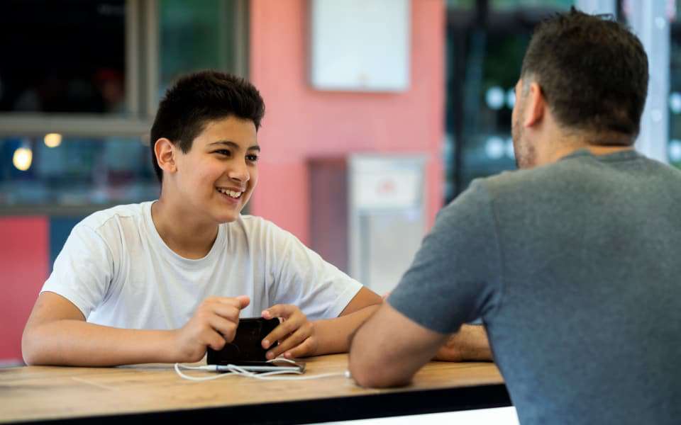 Minderjähriger Flüchtling sitzt seinem Vormund gegenüber an einem Tisch
